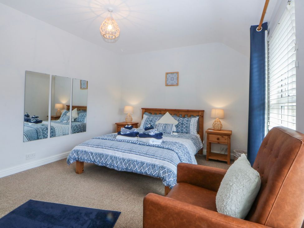 A bedroom with a bed and armchair at Bythynnod Newydd Trefor near Nefyn