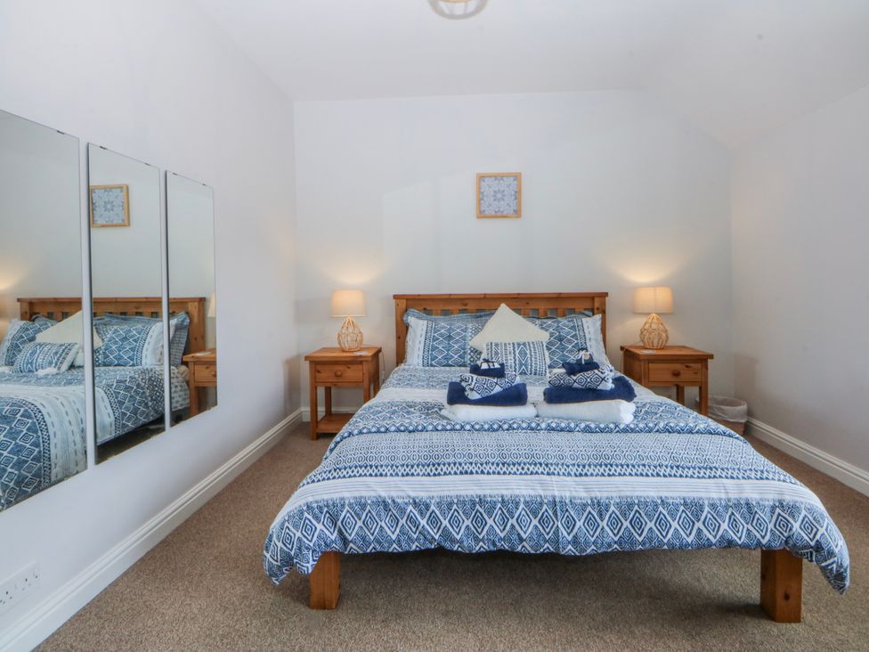 A bedroom with a bed and nightstand at Bythynnod Newydd Trefor near Nefyn