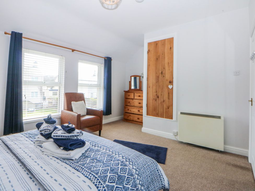 A bedroom with a bed, armchair, and chest of drawers at Bythynnod Newydd Trefor near Nefyn