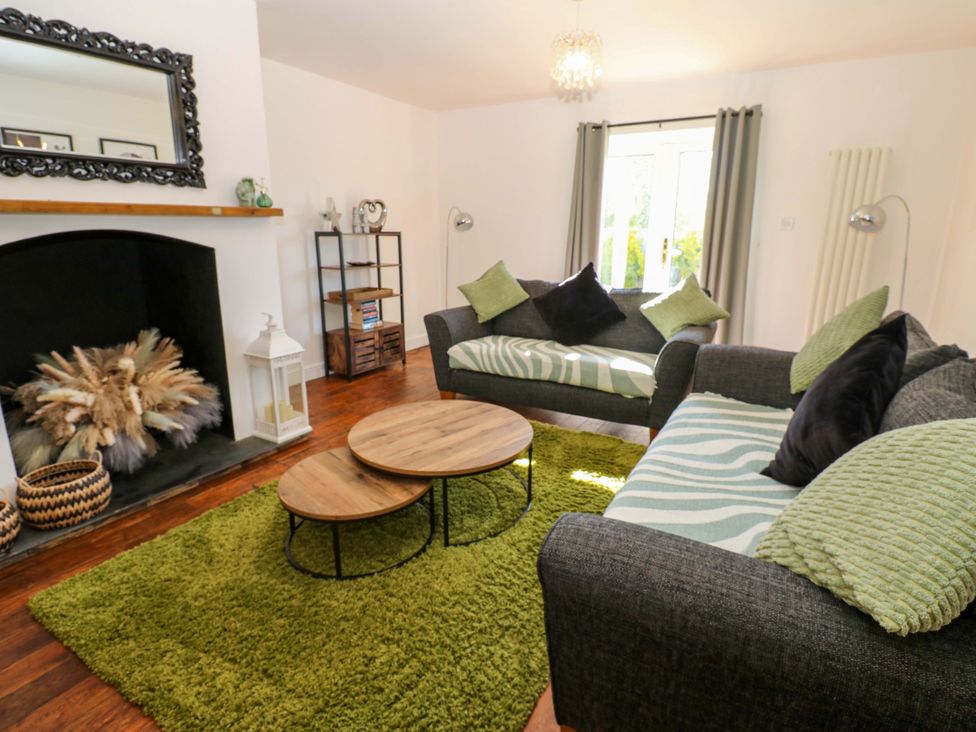 A living room with a sofa and coffee table at Blacksmiths Cottage in Shilbottle