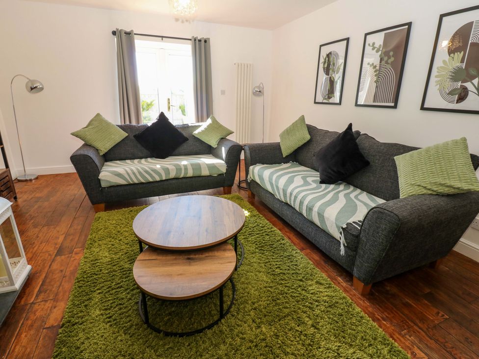 A living room with sofas and a coffee table at Blacksmiths Cottage in Shilbottle