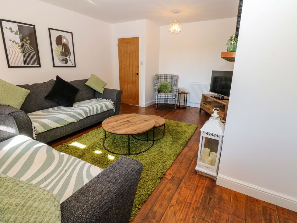 A living room with a sofa and coffee table at Blacksmiths Cottage in Shilbottle