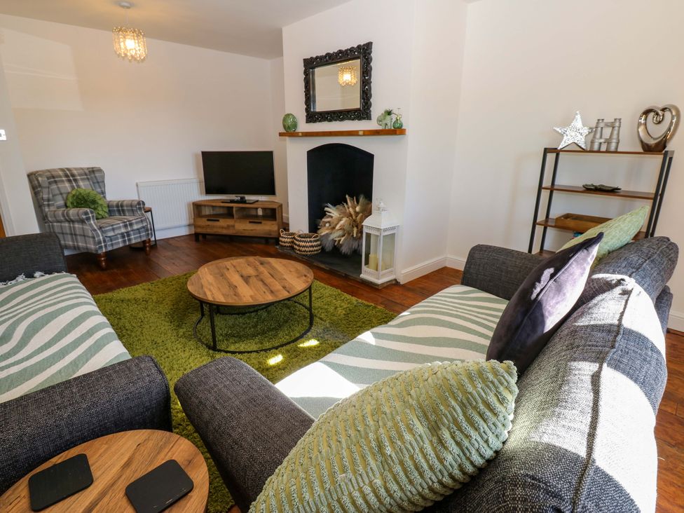 A living room with a coffee table and sofa at Blacksmiths Cottage in Shilbottle