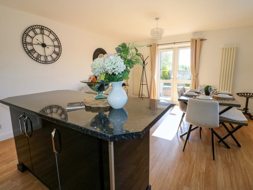 A dining room with a kitchen island and a dining table at Blacksmiths Cottage in Shilbottle