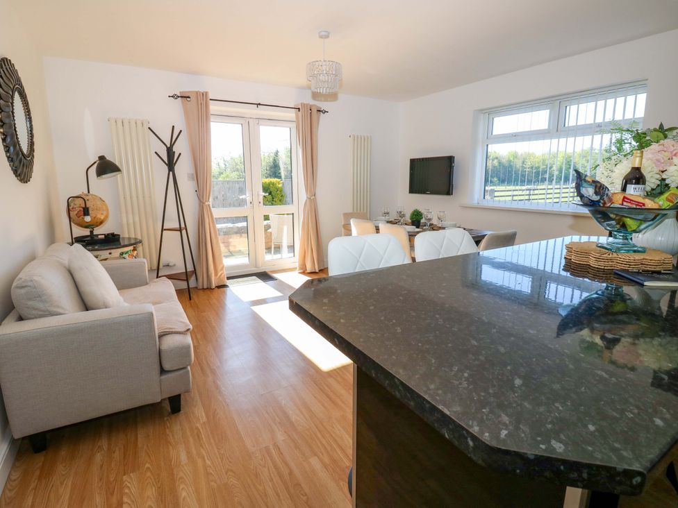 A living room with a sofa and dining area at Blacksmiths Cottage in Shilbottle