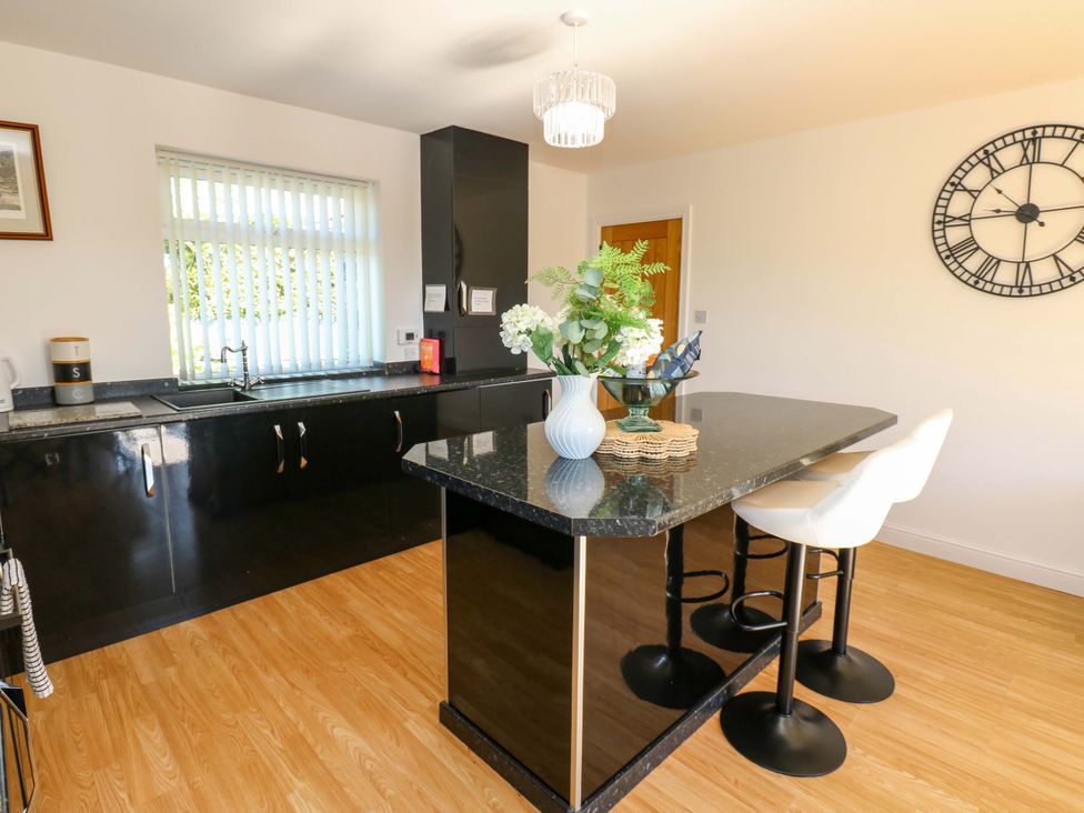 A kitchen with black cabinets and bar stools at Blacksmiths Cottage in Shilbottle