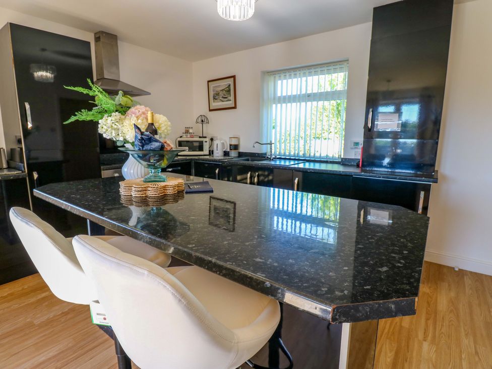 A kitchen with a countertop and stools at Blacksmiths Cottage in Shilbottle