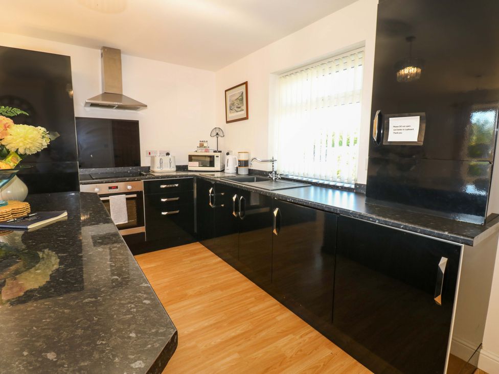 A kitchen with black cabinets and appliances at Blacksmiths Cottage in Shilbottle