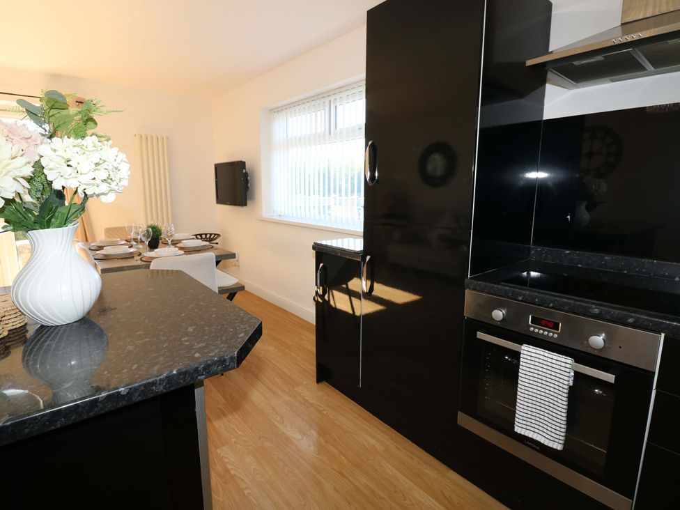 A kitchen with appliances and dining area at Blacksmiths Cottage in Shilbottle