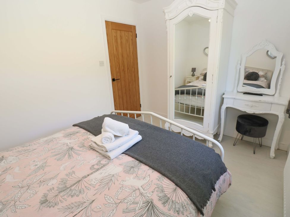 A bedroom with a bed and wardrobe at Blacksmiths Cottage in Shilbottle