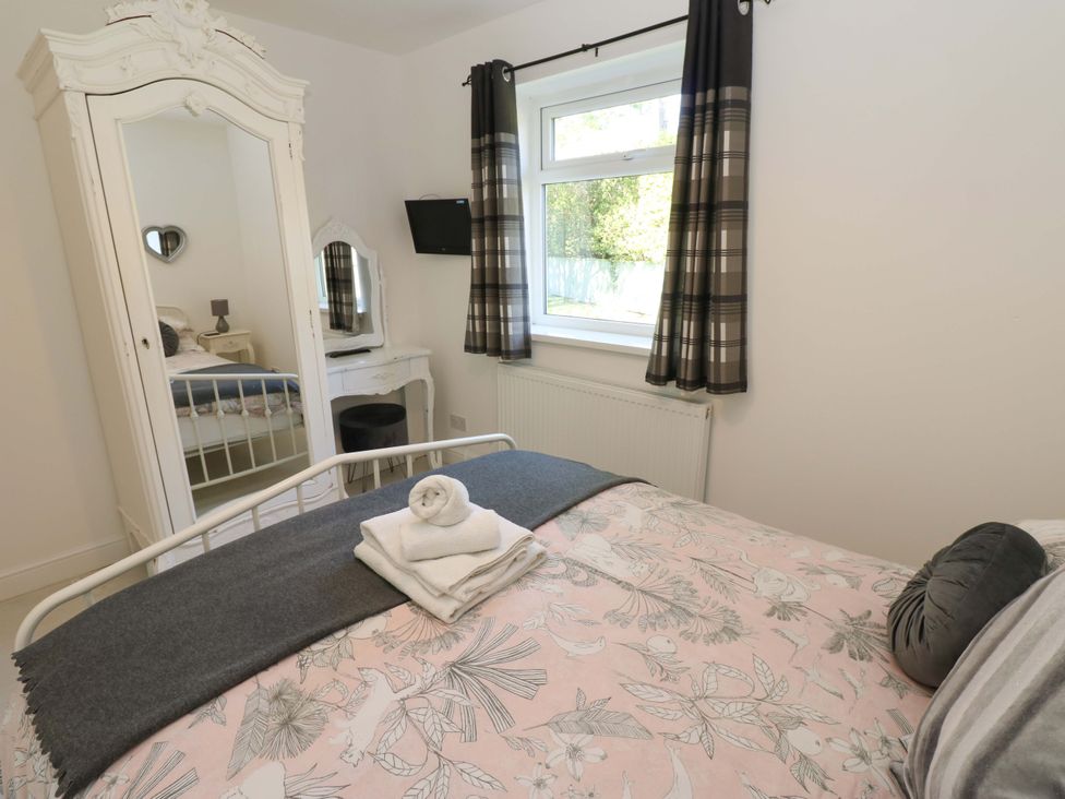 A bedroom with a bed and a mirror at Blacksmiths Cottage in Shilbottle