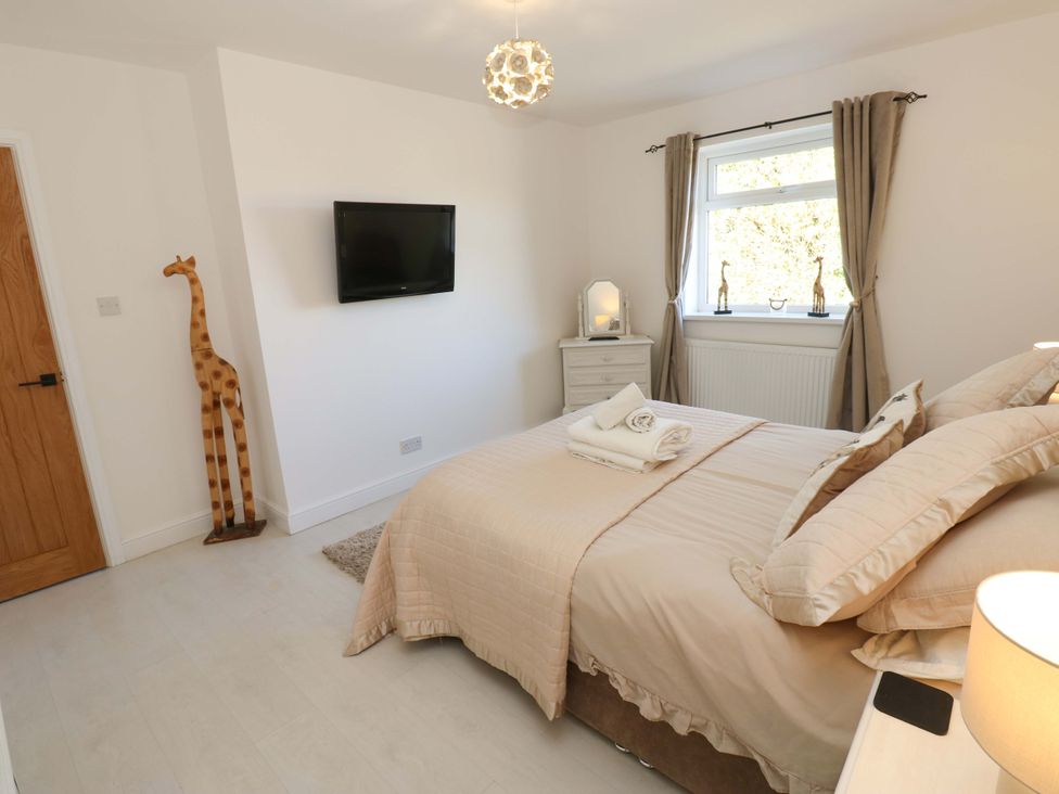 A bedroom with a bed and television at Blacksmiths Cottage in Shilbottle