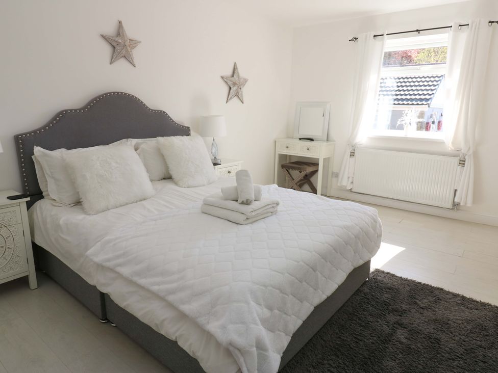 A bedroom with a bed and nightstand at Blacksmiths Cottage in Shilbottle