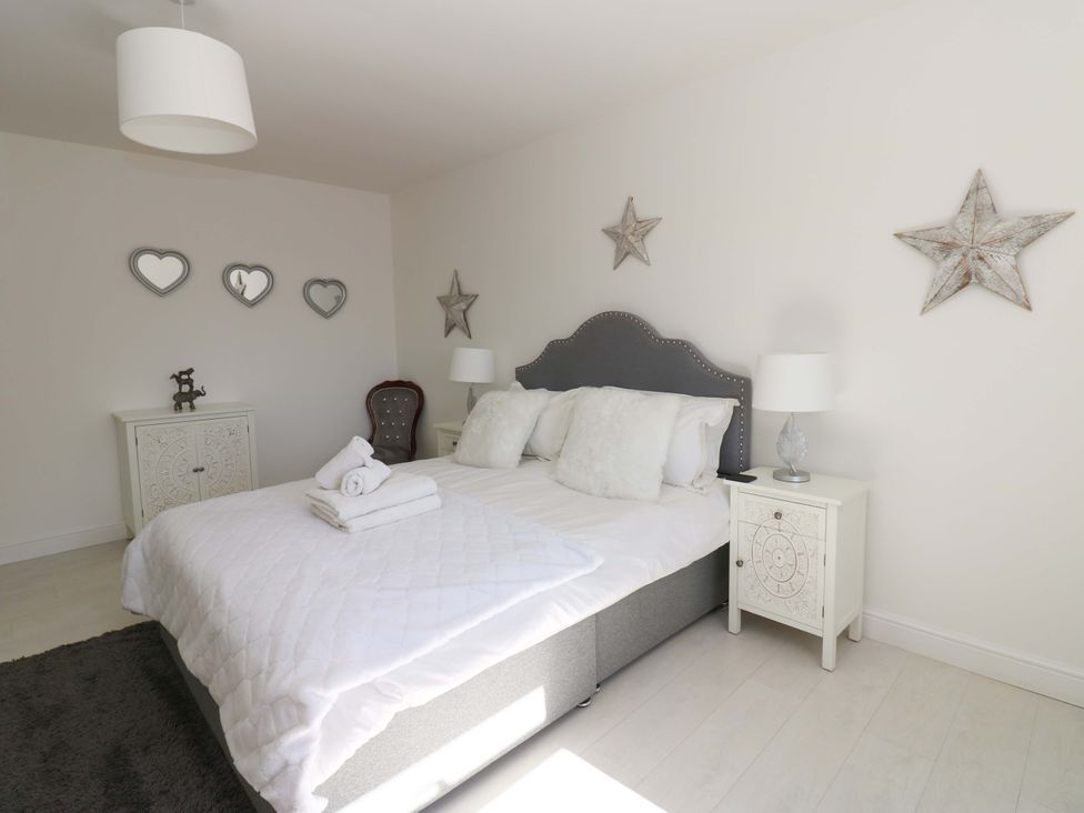 A bedroom with a bed and nightstands at Blacksmiths Cottage in Shilbottle