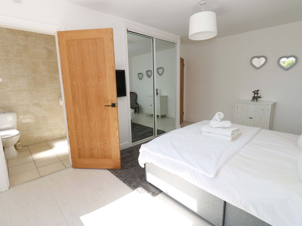 A bedroom with a bed and bathroom door at Blacksmiths Cottage in Shilbottle