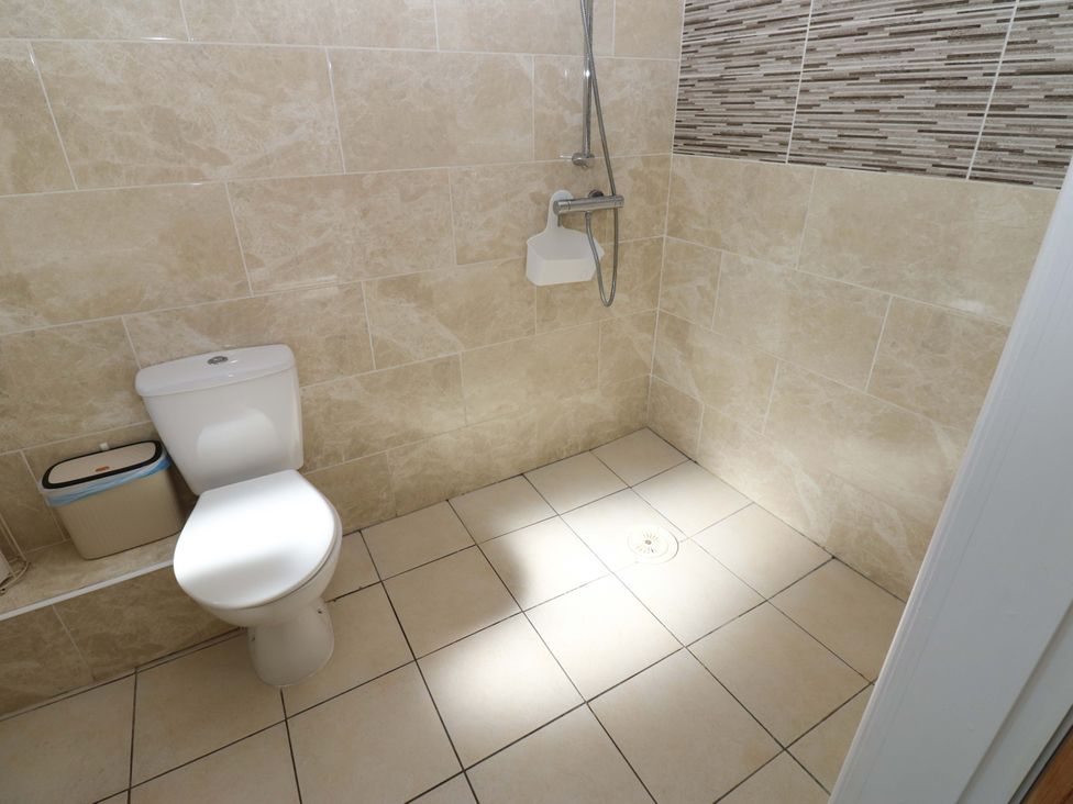 A bathroom with a toilet and shower at Blacksmiths Cottage in Shilbottle