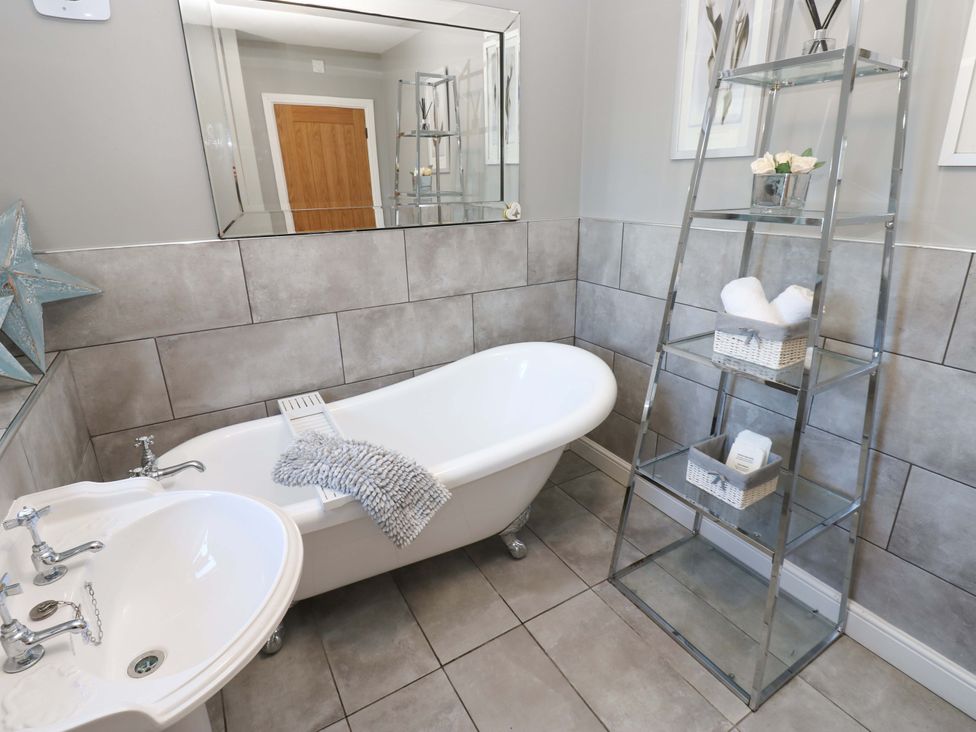 A bathroom with a bathtub and sink at Blacksmiths Cottage in Shilbottle