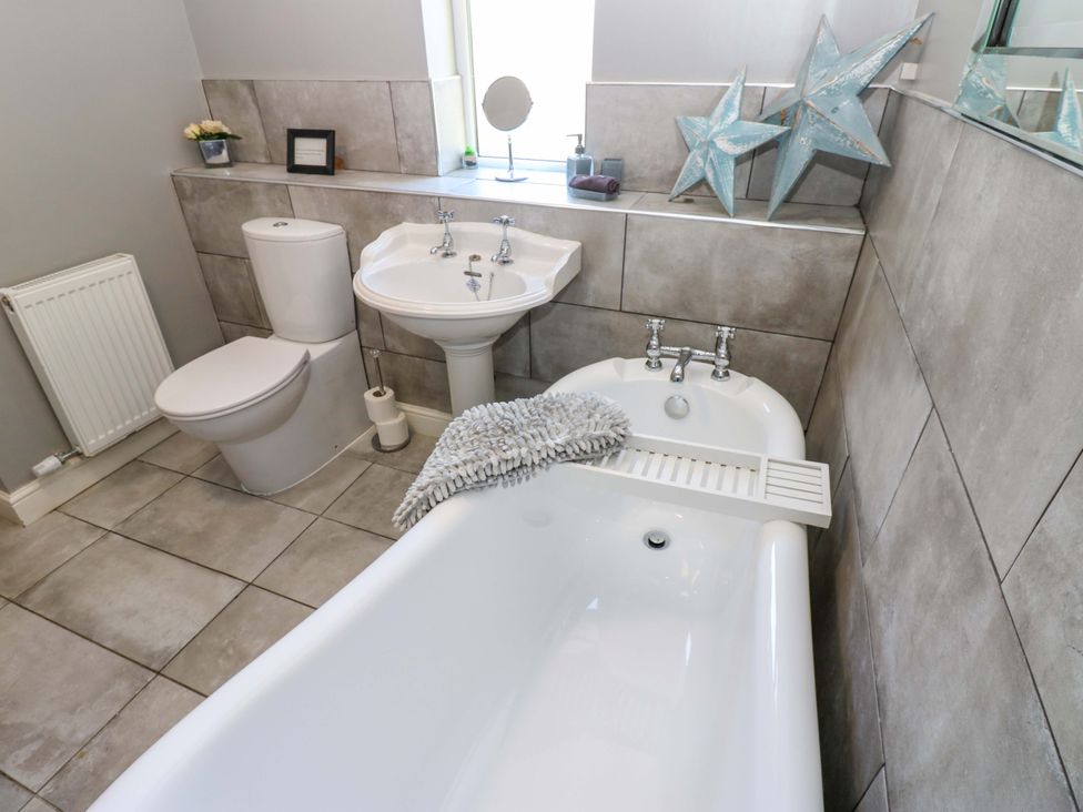 A bathroom with a bathtub sink and toilet at Blacksmiths Cottage in Shilbottle