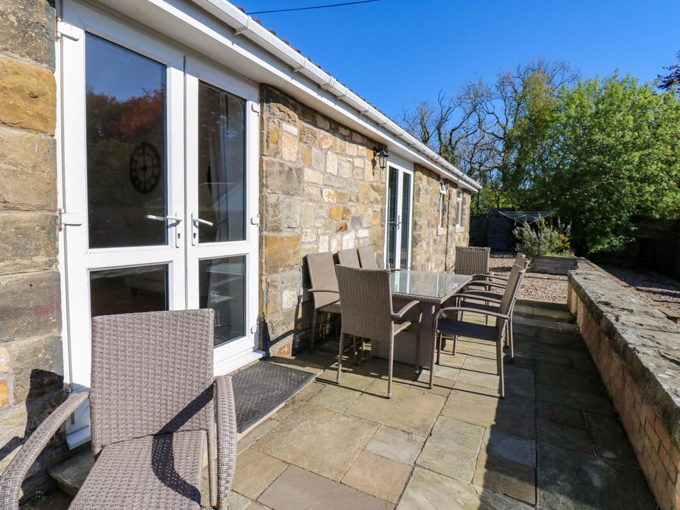 An outdoor patio with a table and chairs at Blacksmiths Cottage in Shilbottle