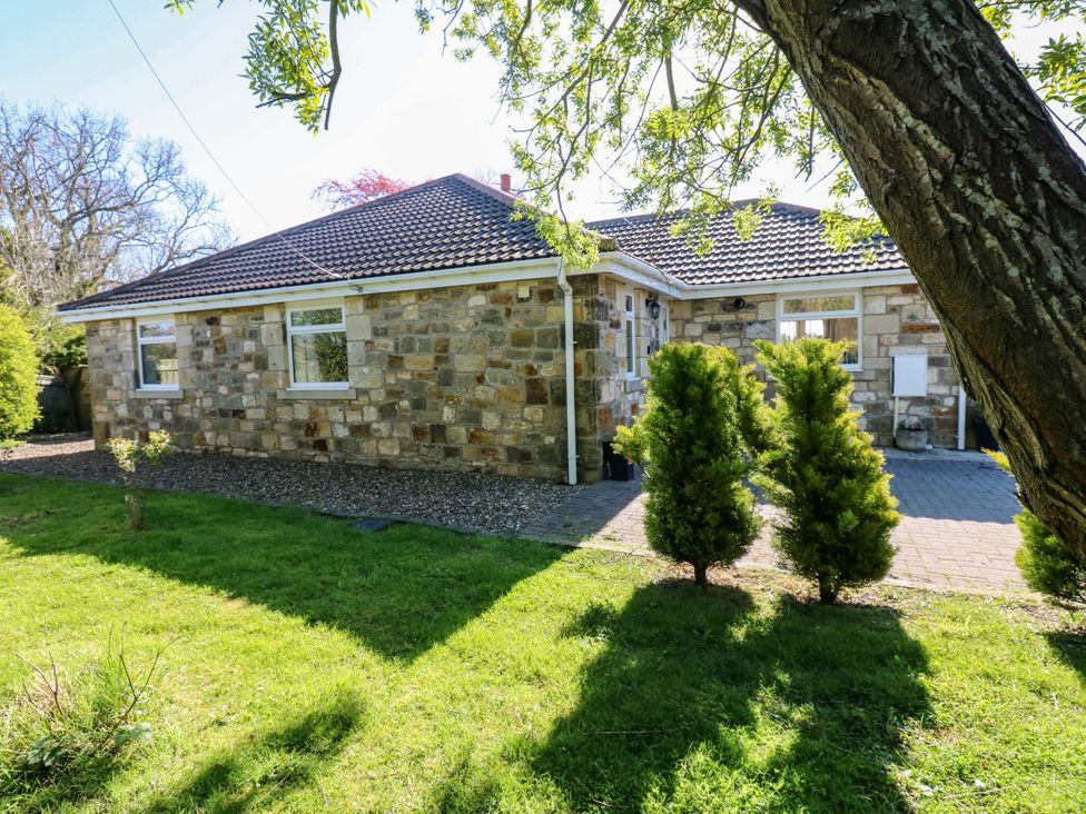 A house surrounded by grass and trees at Blacksmiths Cottage in Shilbottle