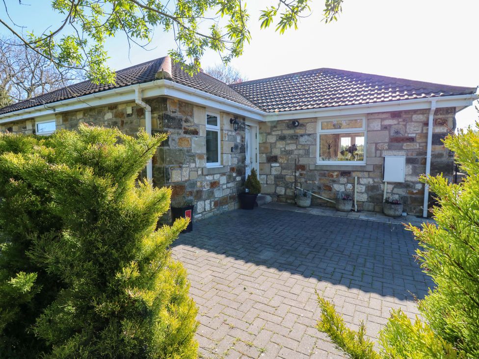 A house with stone walls and a driveway at Blacksmiths Cottage in Shilbottle