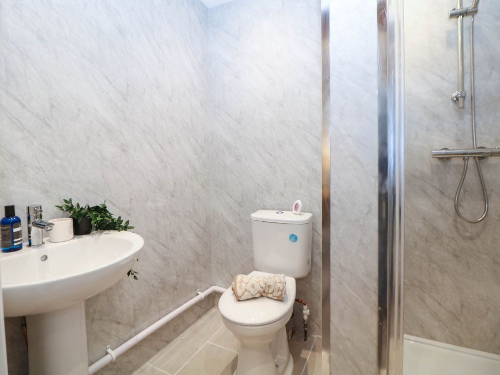 A bathroom with a sink, toilet, shower, and towel at Half Under