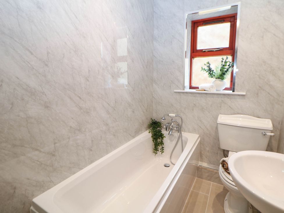 A bathroom with a bathtub, toilet, and sink at Half Under