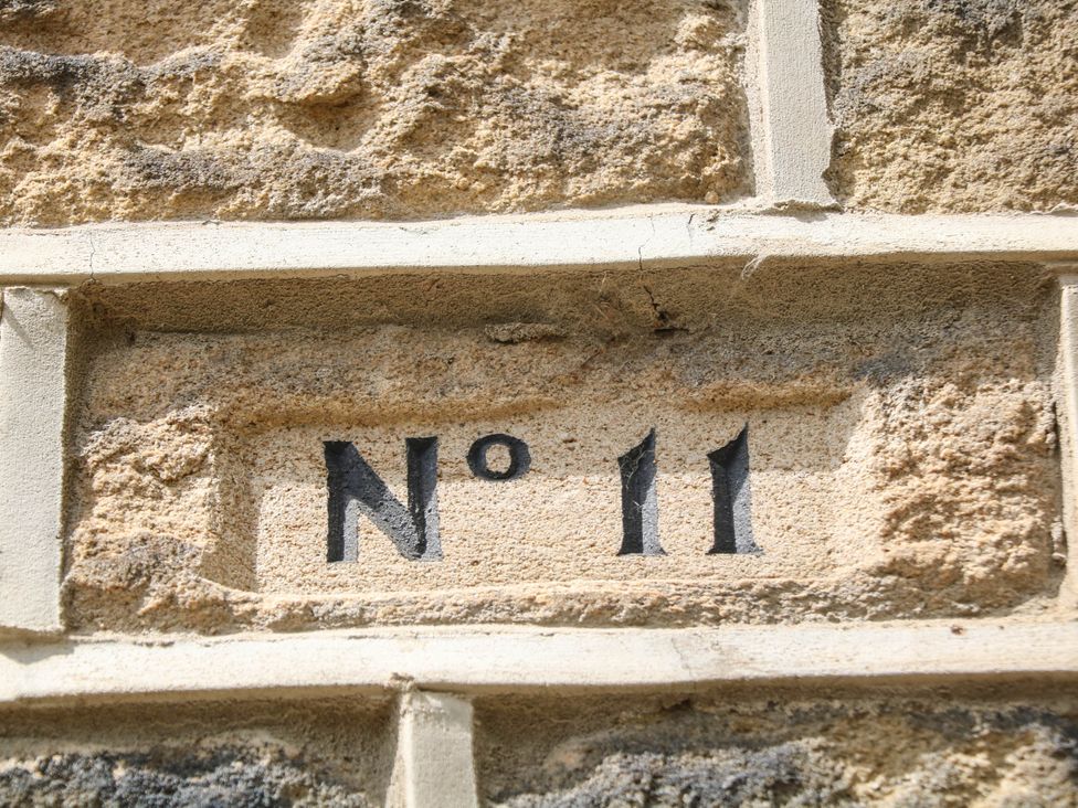 A house number plaque displaying No 11 on a stone wall at Half Under