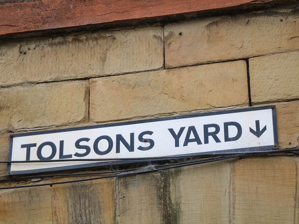 A sign reading 'TOLSONS YARD' mounted on a stone wall