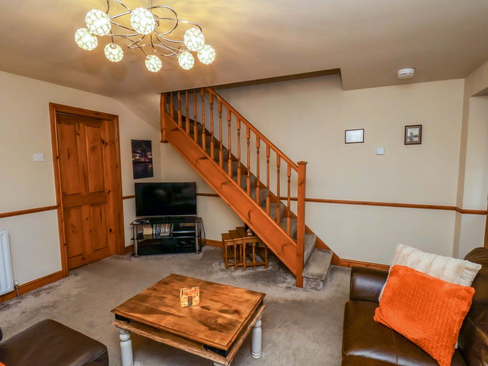 A living room with a staircase and television at Eskview Cottage in Ruswarp near Whitby