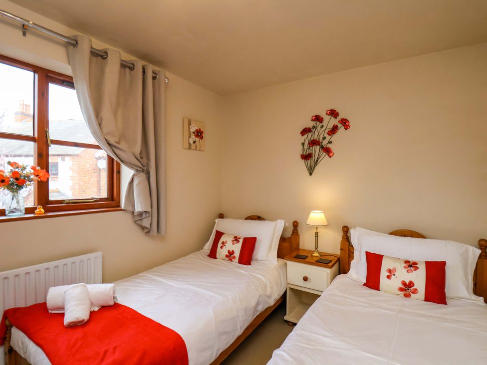 A bedroom with two beds and a nightstand at Eskview Cottage in Ruswarp near Whitby