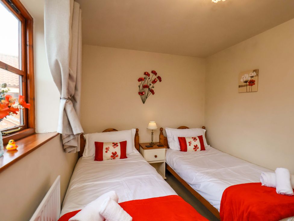 A bedroom with two single beds and a bedside table at Eskview Cottage in Ruswarp near Whitby