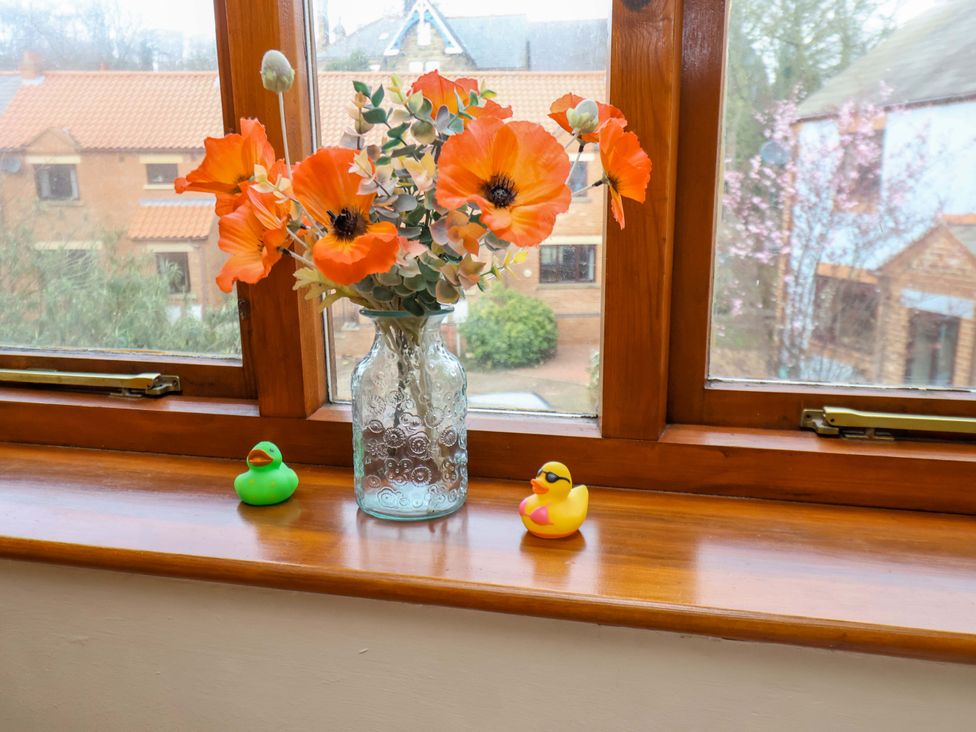 A living room with a vase of flowers and rubber ducks at Eskview Cottage in Ruswarp near Whitby