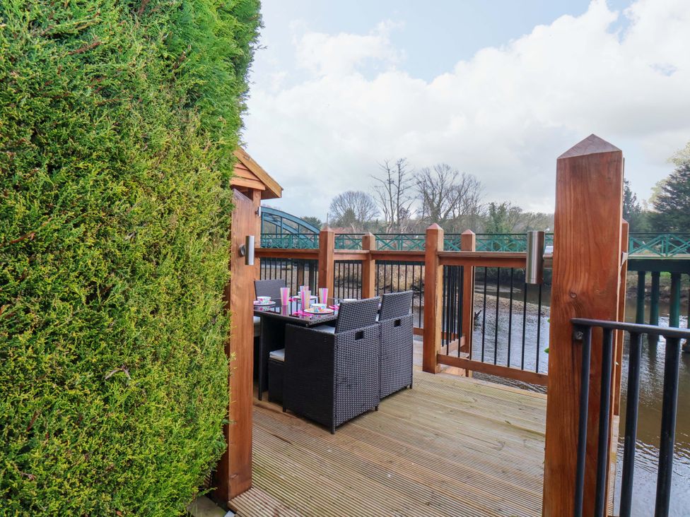 An outdoor area with dining furniture near a river at Eskview Cottage in Ruswarp near Whitby