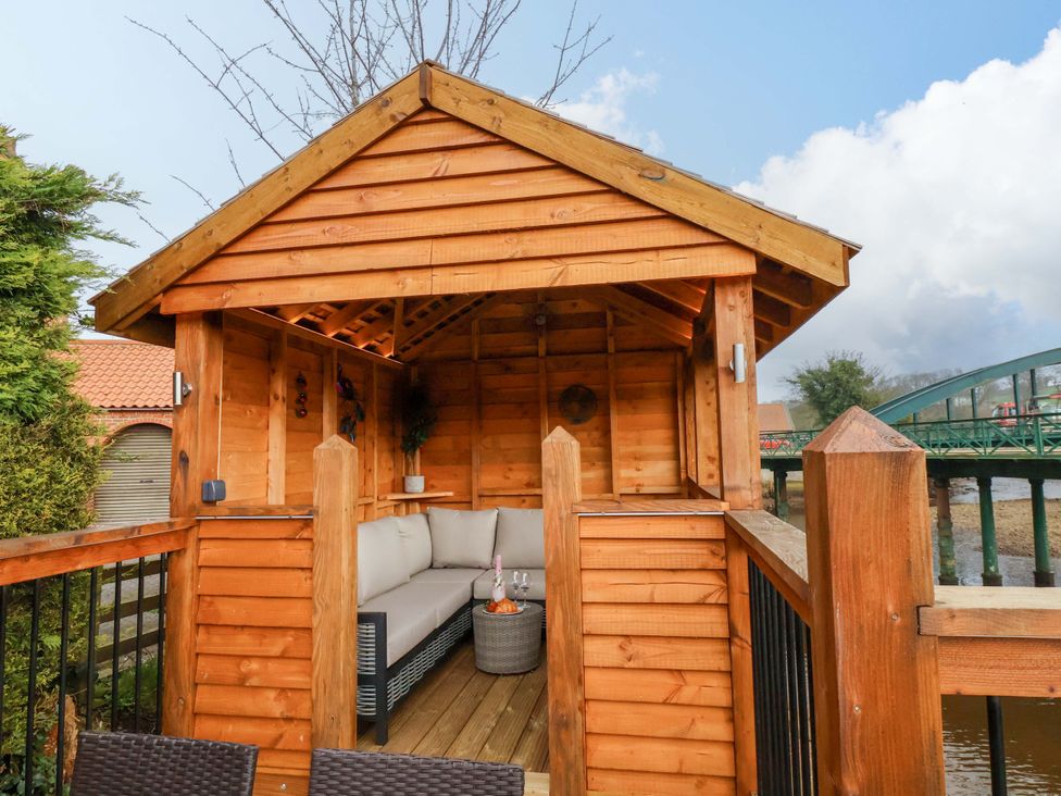 An outdoor seating area with a wooden cabin and sofa at Eskview Cottage in Ruswarp near Whitby