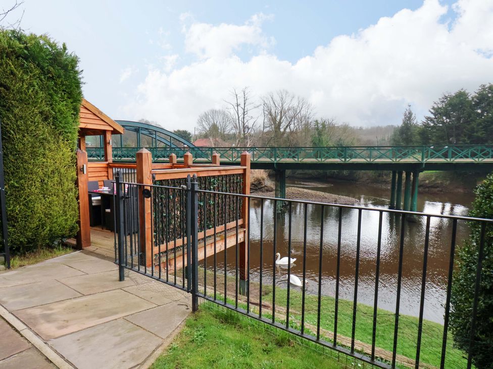 An outdoor area with a wooden structure and a bridge over a river at Eskview Cottage in Ruswarp near Whitby