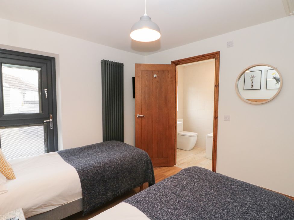 A bedroom with two single beds and a door leading to a bathroom at Fieldside in Hunmanby