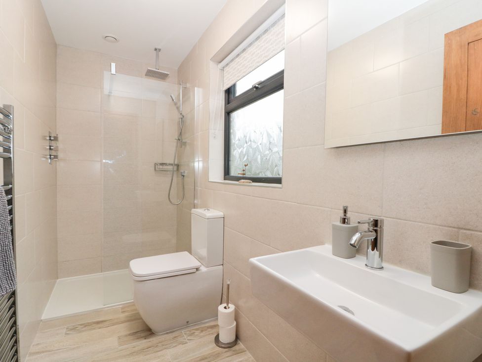 A bathroom with a shower, toilet, sink, and mirror at Fieldside in Hunmanby