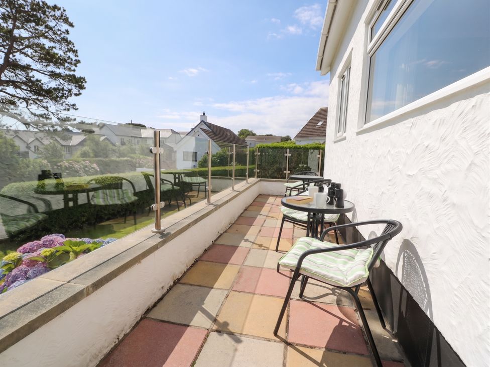 A balcony with tables and chairs at Bay View in Benllech
