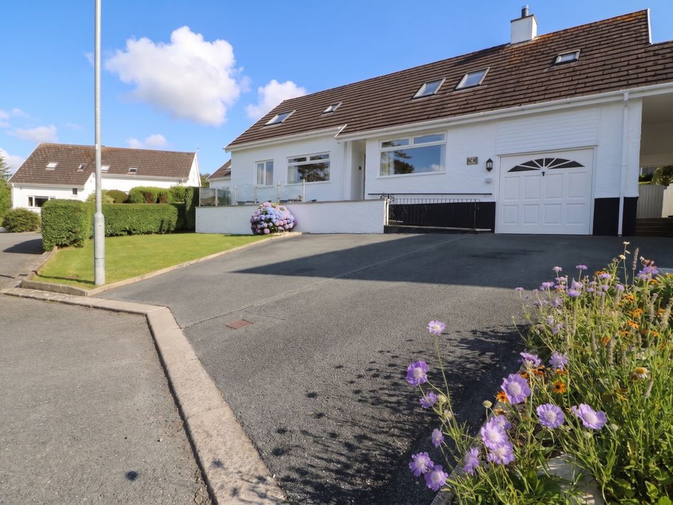 A house with a garage and flower bed at Bay View in Benllech
