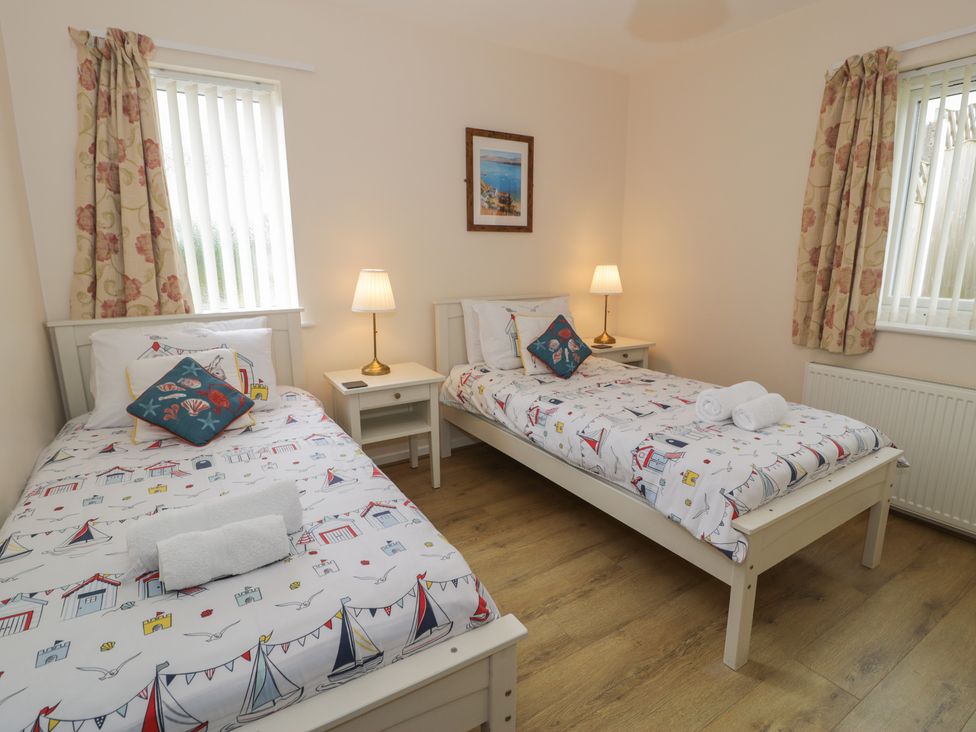 A bedroom with two single beds and bedside tables at Bay View in Benllech