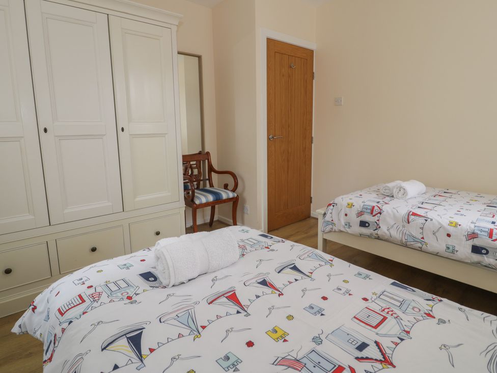 A bedroom with two beds and a wardrobe at Bay View in Benllech