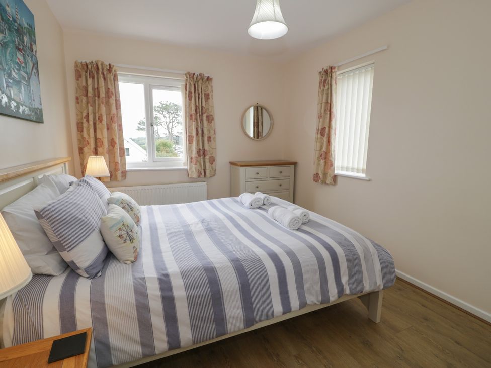 A bedroom with a bed, lamp, and dresser at Bay View in Benllech