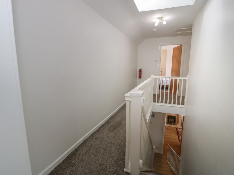 A hallway with a staircase and fire extinguisher at Bay View in Benllech