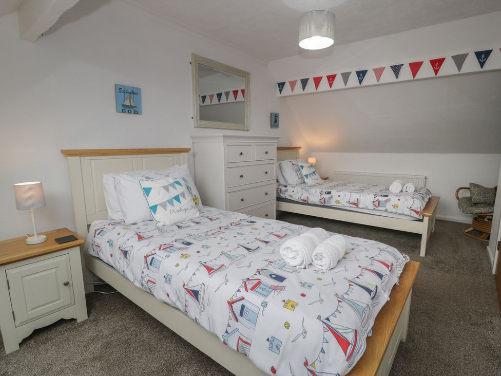 A bedroom with two beds and a dresser at Bay View in Benllech