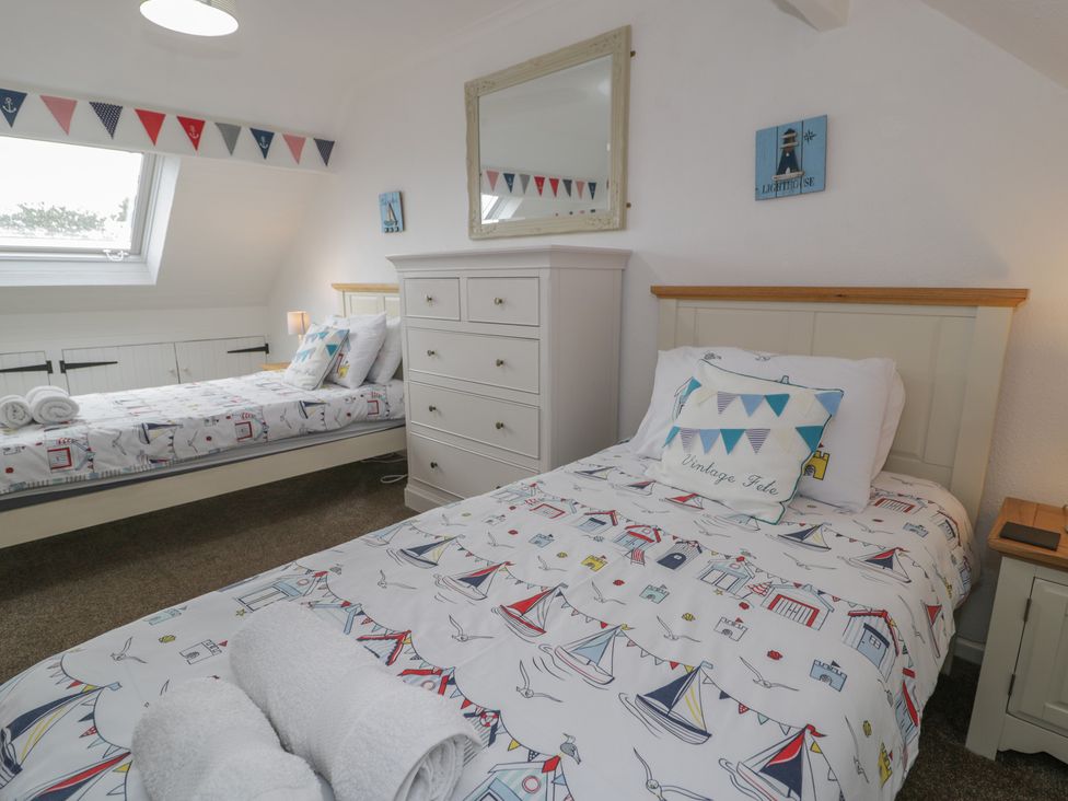 A bedroom with two beds and a dresser at Bay View in Benllech