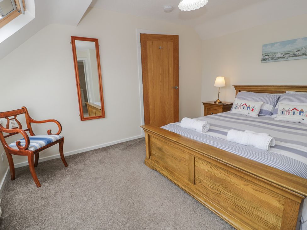 A bedroom with a bed and a chair at Bay View in Benllech