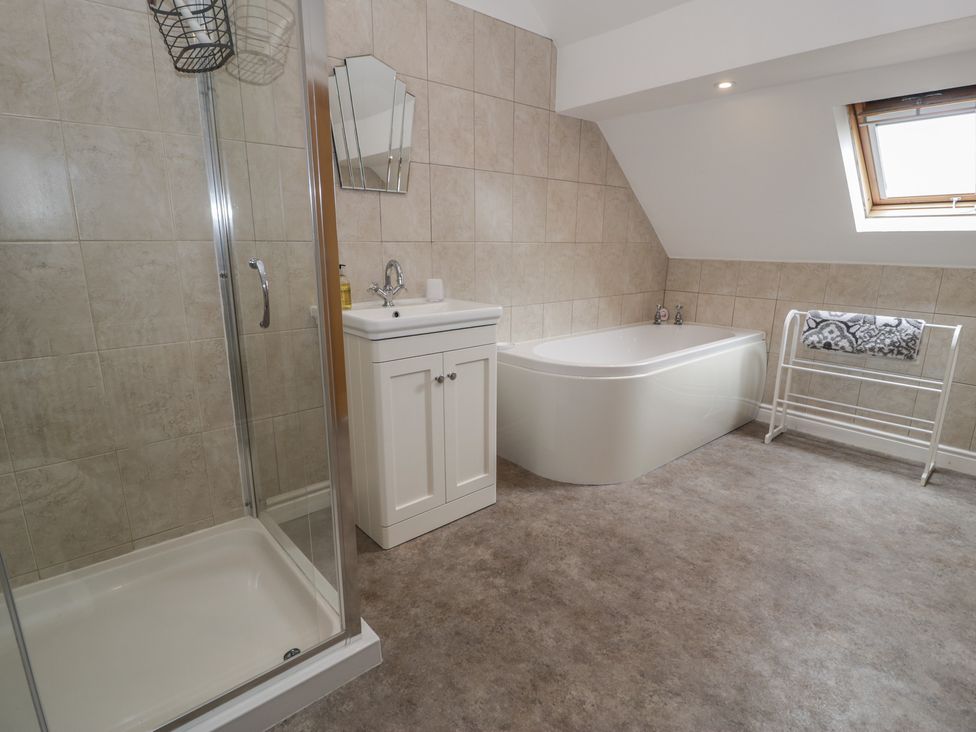 A bathroom with a shower and bathtub at Bay View in Benllech