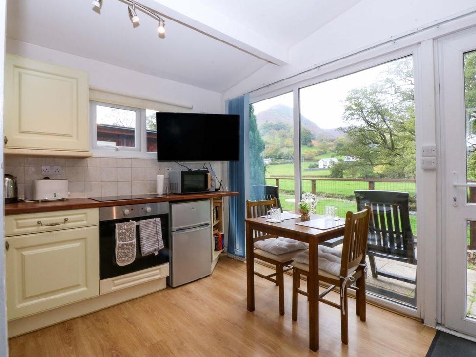 A kitchen with dining table and appliances at River's Nook in Llangynog