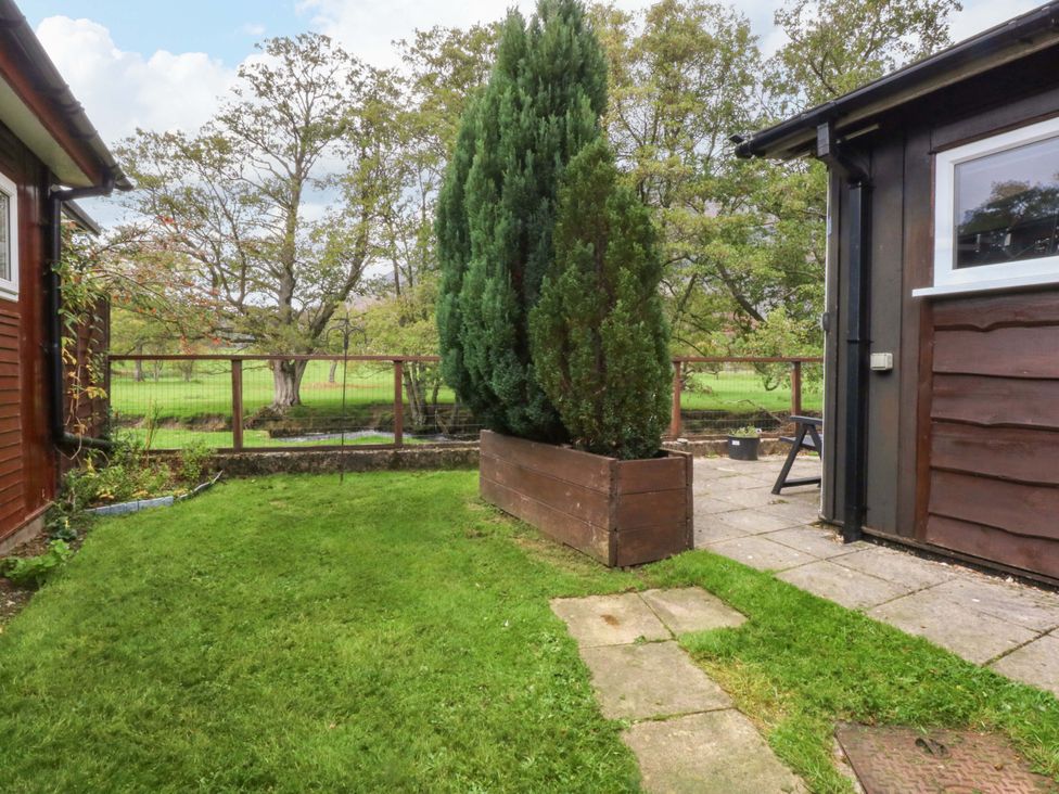 A garden with grass and a tree at River's Nook in Llangynog